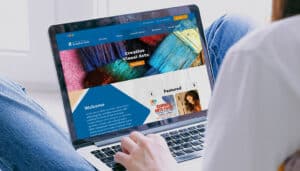 A laptop displays a colorful website for Creative Visual Arts, showcasing vibrant art supplies and featured arts events, with a soft background.