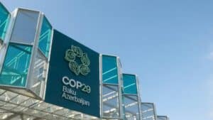 COP29 sign displayed prominently at the Baku venue, featuring teal accents and stylized logo against a clear blue sky.